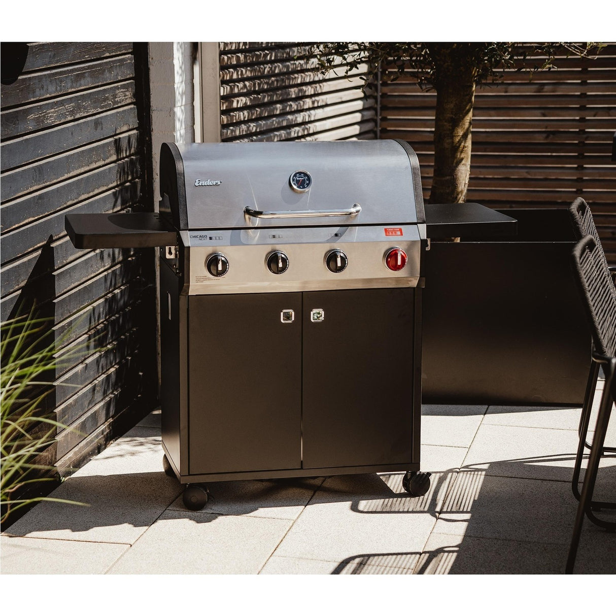 Outdoor grill on a patio with a wooden fence in the background